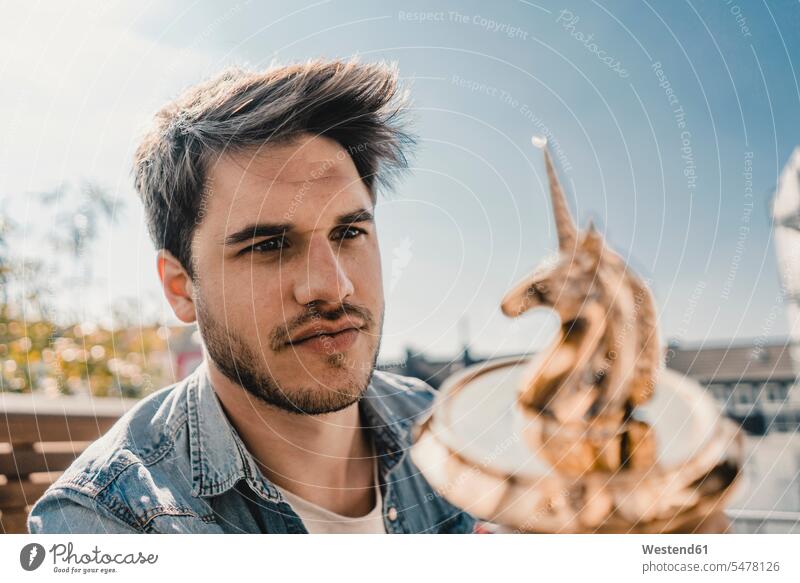 Young entrepreneur looking at unicorn figurine hold Individuality Distinct individual creative Visions balconies location shot location shots outdoor