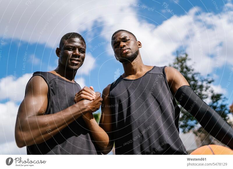 Basketball players handshaking on outdoor basketball court human human being human beings humans person persons African black black ethnicity coloured 2
