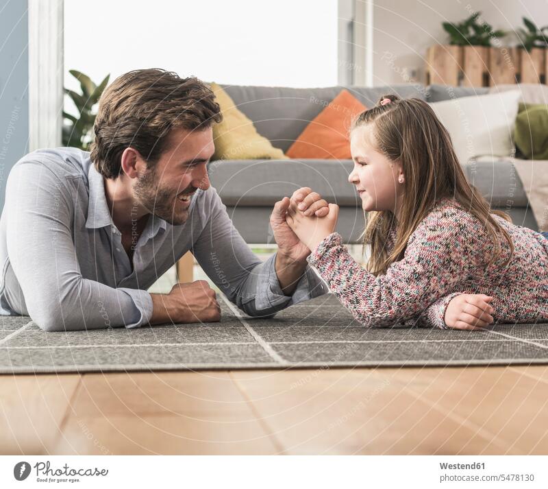 Young man and little girl lying on ground, arm wrestling caucasian caucasian ethnicity caucasian appearance european laying down lie lying down floor floors