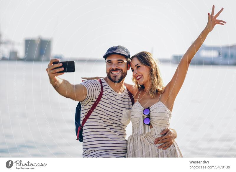 Spain, Andalusia, Malaga, happy tourist couple taking selfie with smartphone at the coast coastline shoreline Selfie Selfies tourists happiness Smartphone