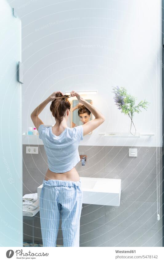 Rear view of young woman in bath room basin basins mirrors telecommunication phones telephone telephones cell phone cell phones Cellphone mobile mobile phones