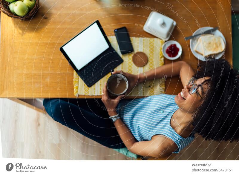 Businesswoman with digital tablet and breakfast on desk contemplating while sitting at home color image colour image casual clothing casual wear leisure wear