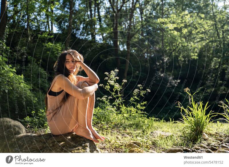 Portrait of young woman sitting on a rock in the forest, Garrotxa, Spain human human being human beings humans person persons caucasian appearance