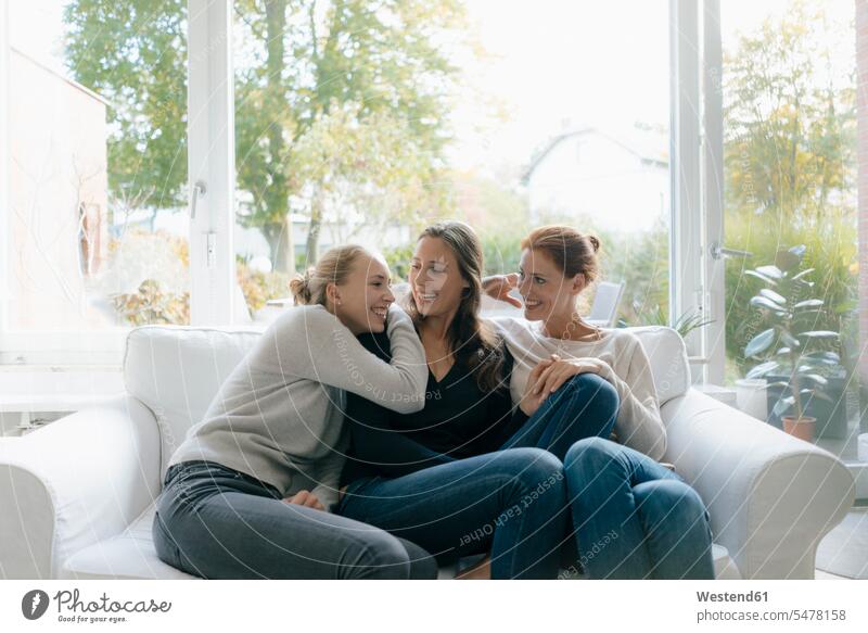 Happy mother with two teenage girls on couch at home settee sofa sofas couches settees Teenage Girls female teenagers daughter daughters mommy mothers mummy