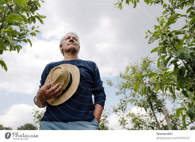 Man holding hat standing against sky in field color image colour image outdoors location shots outdoor shot outdoor shots day daylight shot daylight shots