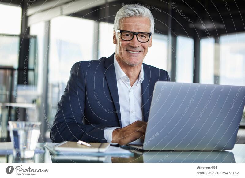Businessman working in office, using laptop mature men mature man using a laptop Using Laptops At Work Office Offices desk desks Business man Businessmen