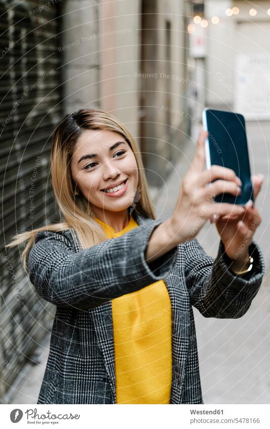 Young woman taking selfie with her smartphone in city jumper sweater Sweaters telecommunication phones telephone telephones cell phone cell phones Cellphone