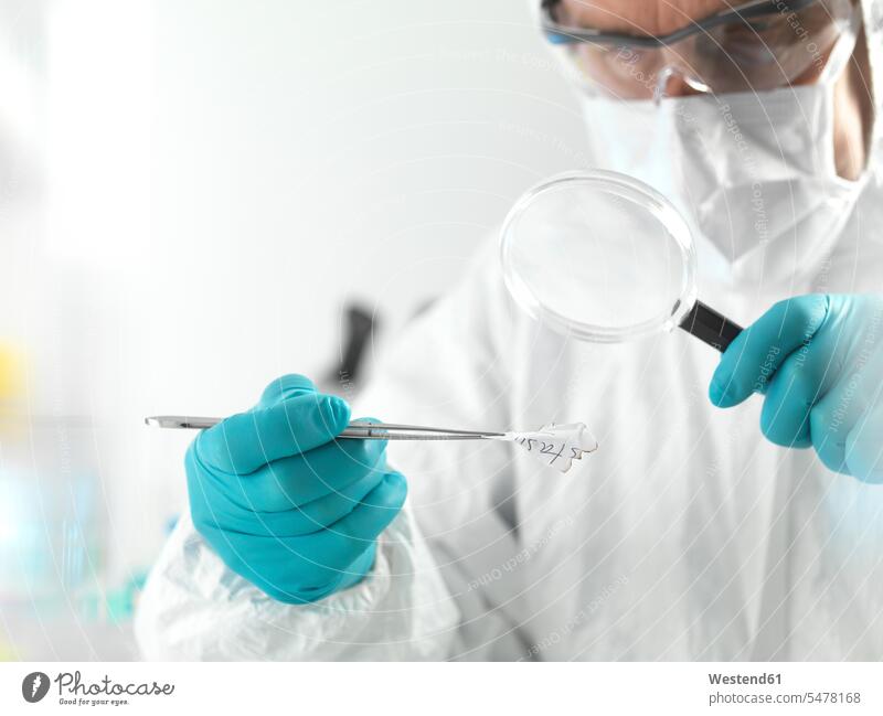 Forensic scientist examining fragments of paper in a laboratory (value=0) human human being human beings humans person persons caucasian appearance