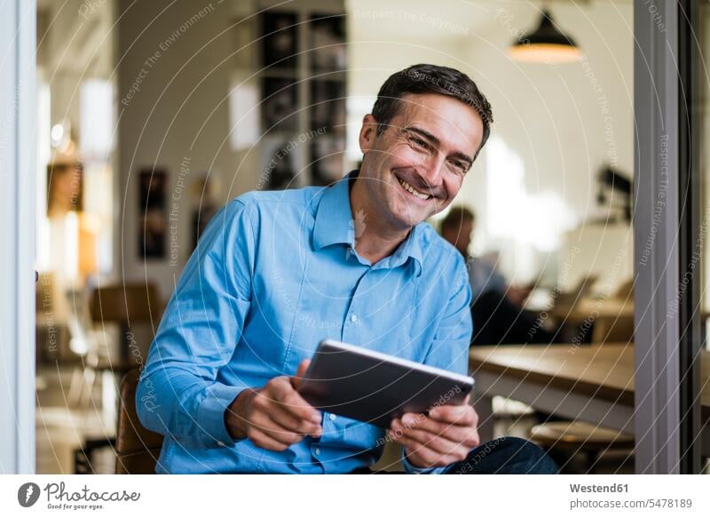 Smiling businessman with tablet sitting at open French door digitizer Tablet Computer Tablet PC Tablet Computers iPad Digital Tablet digital tablets Seated