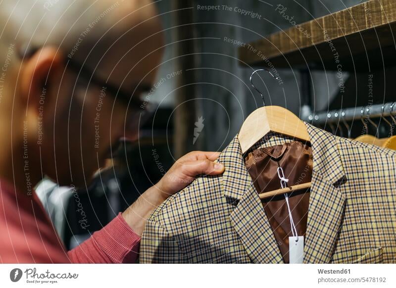 Man looking at jacket in menswear shop man males customer clientele clients customers eyeing men's fashion Adults grown-ups grownups adult people persons