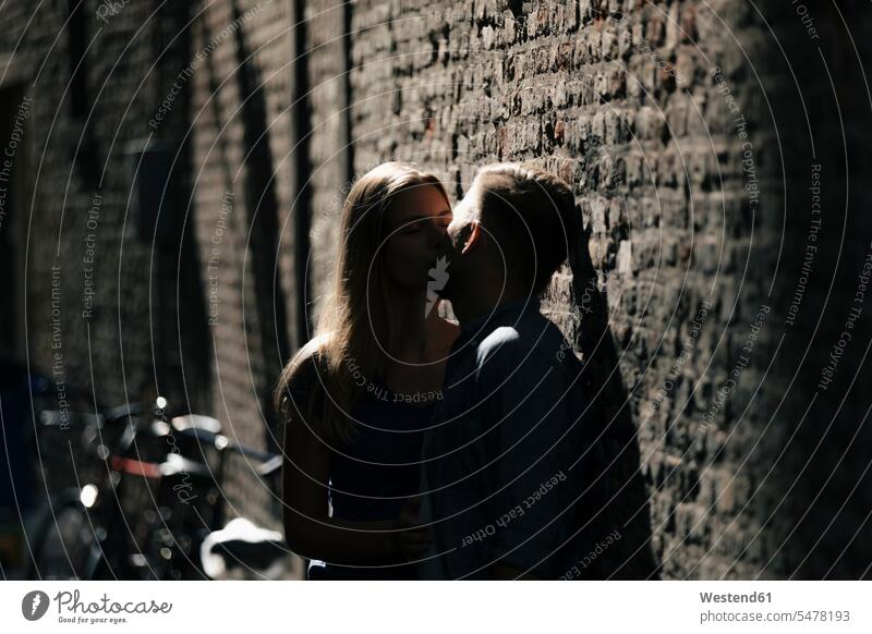 Affectionate young couple kissing at brick wall brick walls kisses twosomes partnership couples people persons human being humans human beings bricks