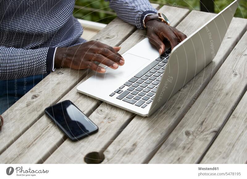 Male professional using laptop at wooden table color image colour image outdoors location shots outdoor shot outdoor shots day daylight shot daylight shots
