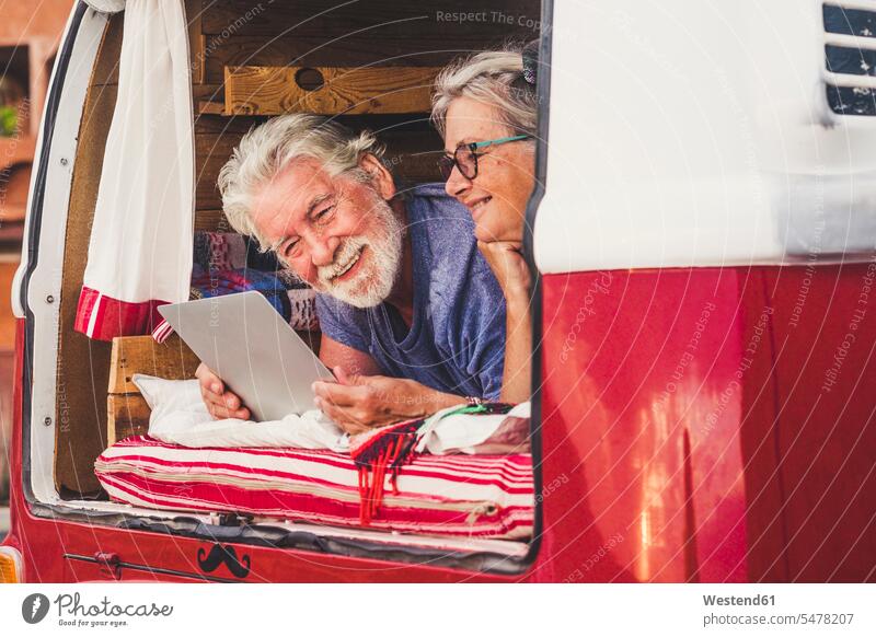Senior couple traveling in a vintage van, lying in boot, using digital tablet touristic tourists transport motor vehicles road vehicle road vehicles Auto