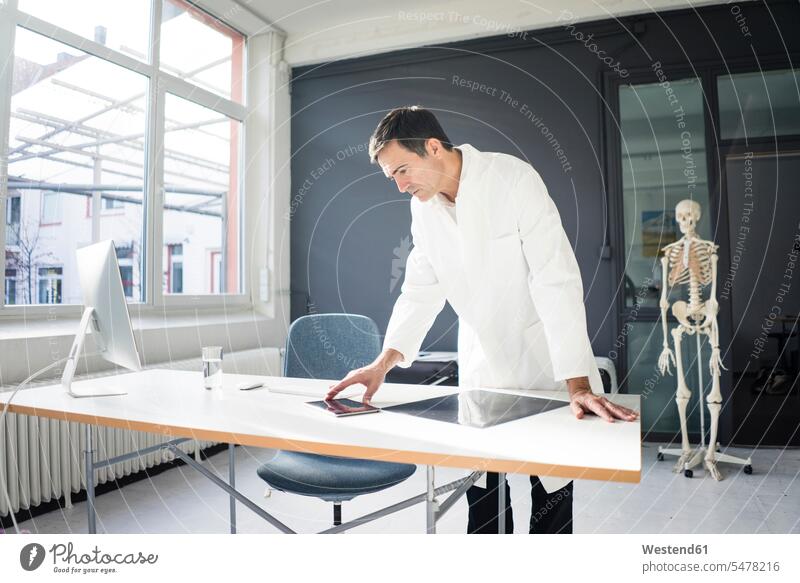 Doctor in medical practice with skeleton in background doctor physicians doctors medical practices Doctors Office Doctor's Office healthcare and medicine