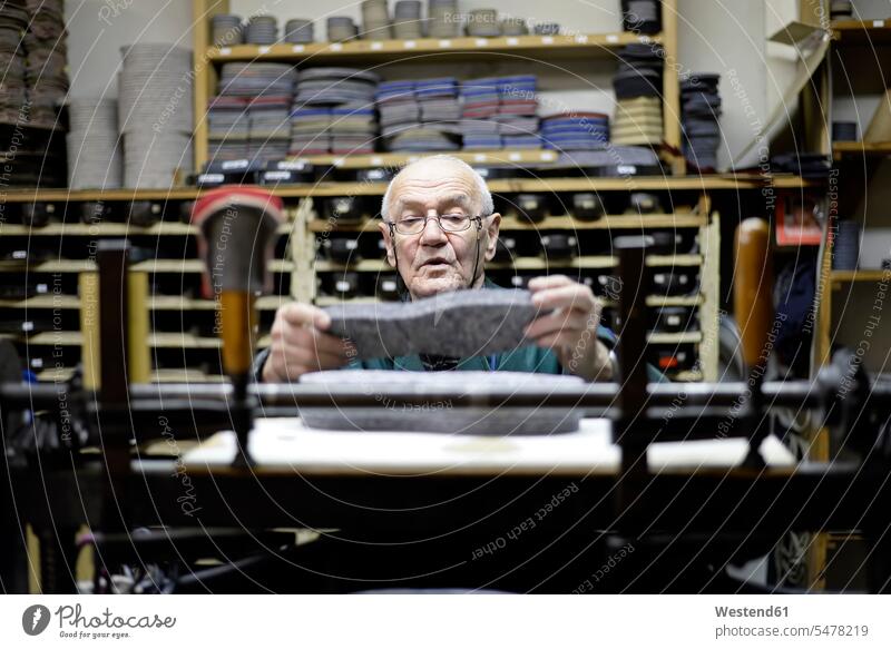 Senior shoemaker working with old-fashioned punching machine in workshop At Work cobbler senior men senior man elder man elder men senior citizen craft crafts