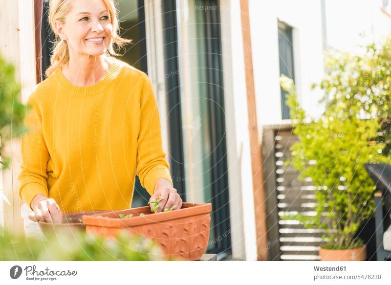 Portrait of smiling mature woman gardening on terrace jumper sweater Sweaters relax relaxing smile delight enjoyment Pleasant pleasure indulgence indulging