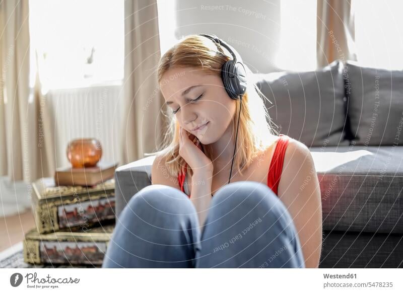 Portrait of young woman with eyes closed sitting on the floor at home listening music with headphones human human being human beings humans person persons