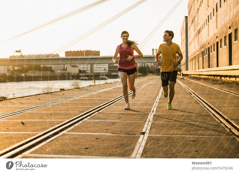 Smiling male and female friends jogging at harbor color image colour image outdoors location shots outdoor shot outdoor shots front view frontal head on