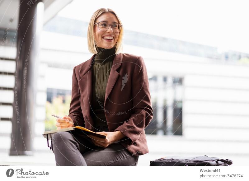 Smiling young businesswoman with notebook in the city human human being human beings humans person persons caucasian appearance caucasian ethnicity european 1