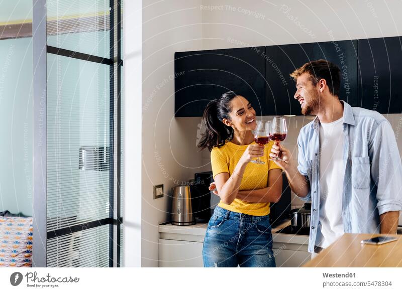 Happy young couple drinking wine in the kitchen at home together Drinking Glass Drinking Glasses Wine Glasses Wineglass Wineglasses hold smile delight enjoyment