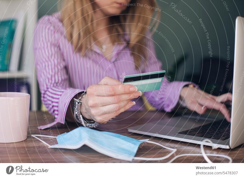 Businesswoman holding credit card making online payment over laptop in office color image colour image indoors indoor shot indoor shots interior interior view