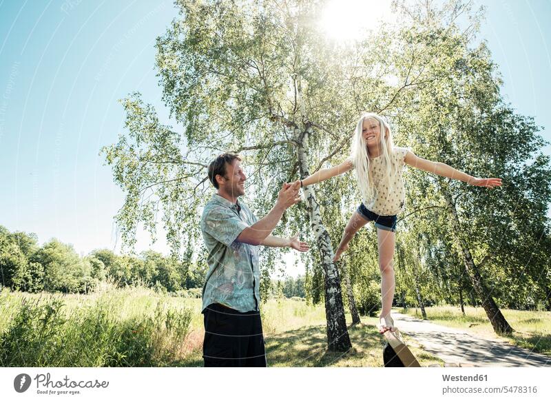 Father helping daughter balancing on a bench in park balanced Equilibrium smile play seasons spring season Spring Time springtime summer time summertime summery