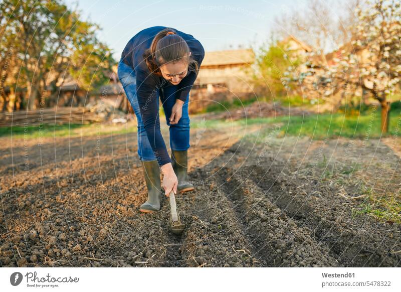 Full length of woman using hand plow on soil while gardening during weekend outdoors location shots outdoor shot outdoor shots day daylight shot daylight shots