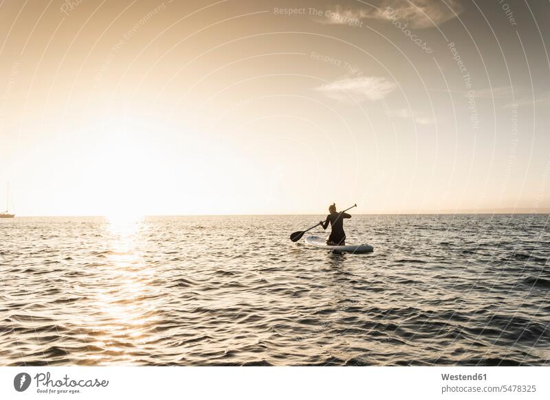 Young woman stand up paddle surfing at sunset Paddle Surfing SUP Stand up paddle surfing paddleboarding Stand Up Paddling paddle boarding standup paddleboarding