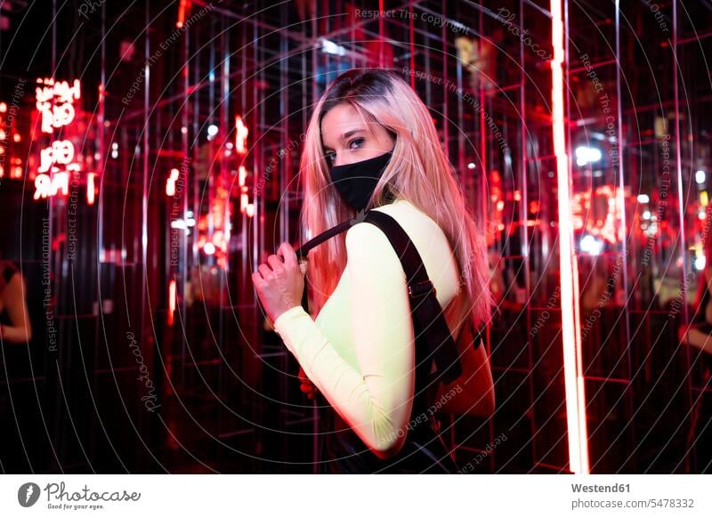 Young woman wearing protective face mask standing in red light room color image colour image indoors indoor shot indoor shots interior interior view Interiors