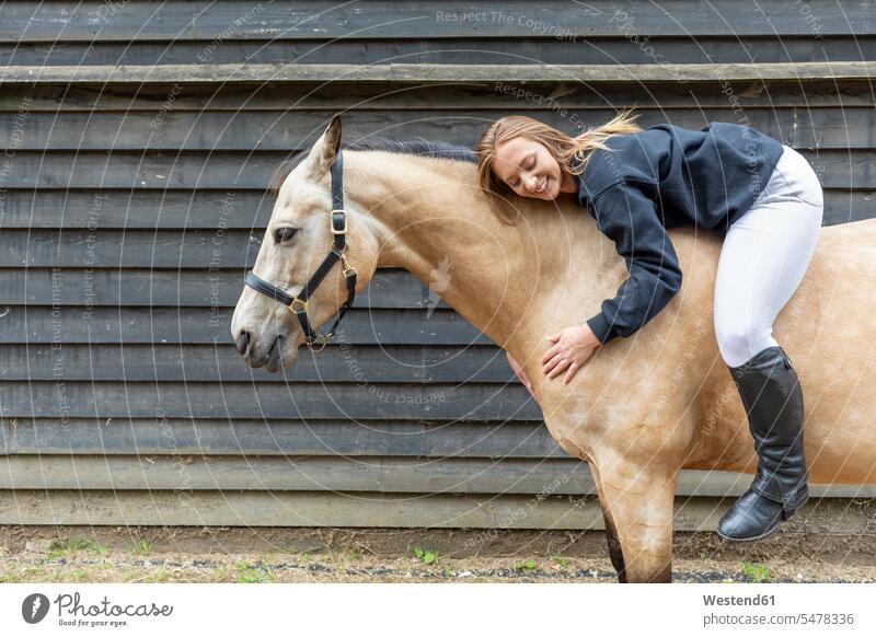 Young woman lying on the back of her horse smile big smile laughing open smile confident human human being human beings humans person persons 1 one person only