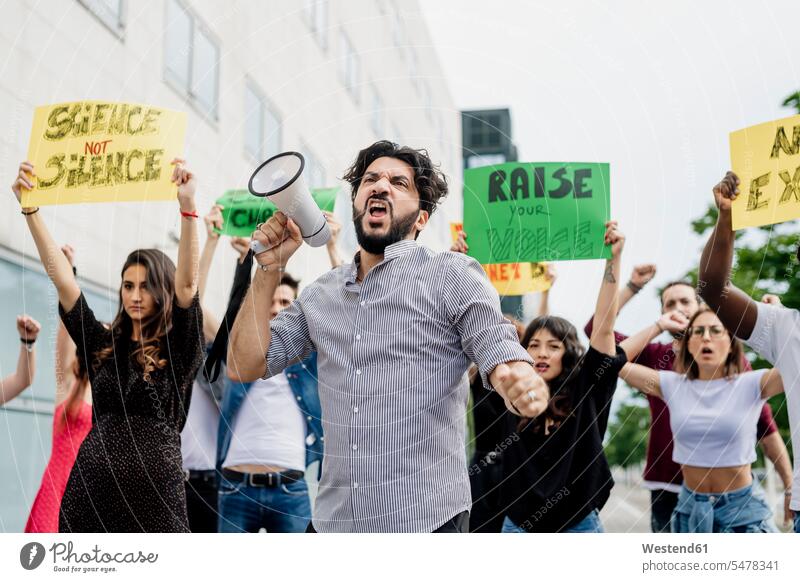 Man screaming through megaphone while protesting with people on street in city color image colour image casual clothing casual wear leisure wear casual clothes