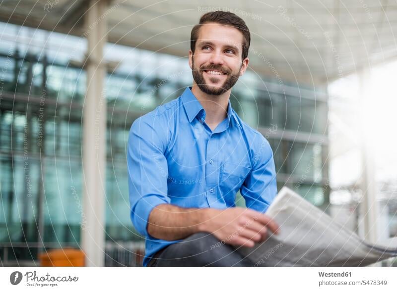 Smiling young businessman sitting outdoors with newspaper smiling smile newspapers Seated Businessman Business man Businessmen Business men business people