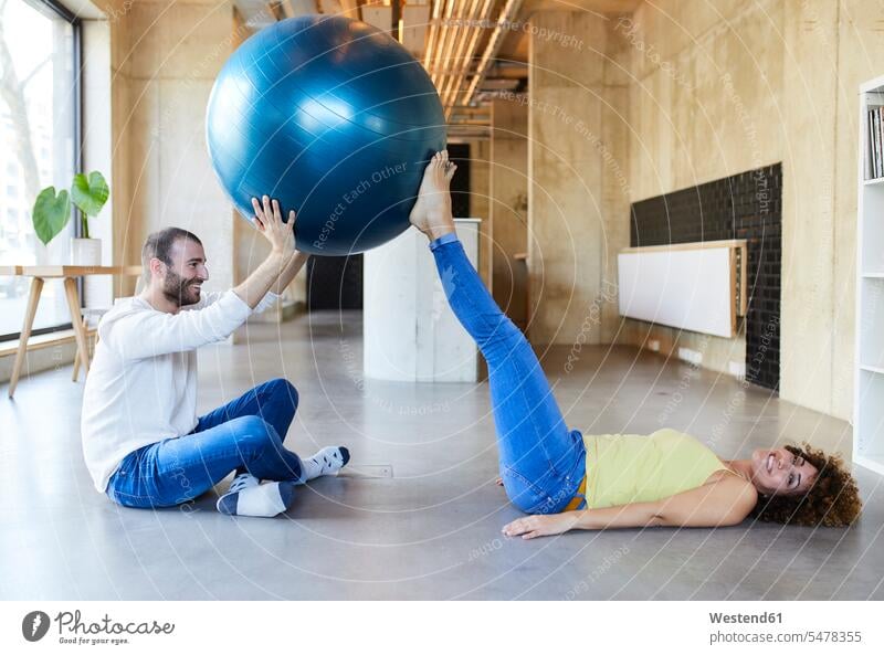 Happy man and woman practicing with fitness ball in modern office Germany freelancer freelancing employee employess Female Colleague resting exercise exercises