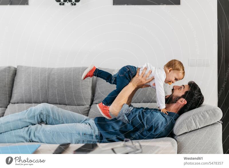 Father playing with his daughter at home lifting father pa fathers daddy dads papa childhood couch settee sofa sofas couches settees Pretending To Fly