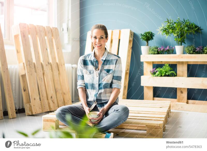 Beautiful woman taking a break from refurbishing her home with pallets, drinking coffee Coffee furnishing females women flat flats apartment apartments