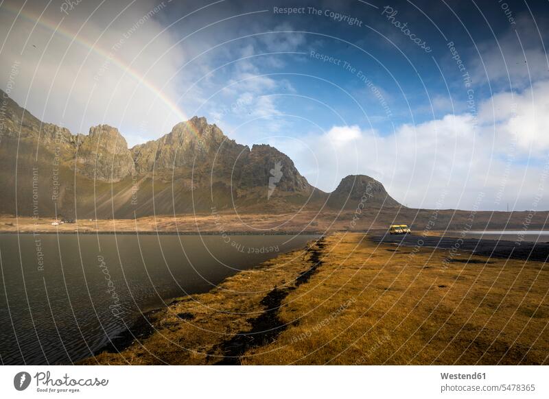 Scenic view of sea amidst mountains against rainbow in sky at Hvalnes Nature Reserve Beach, Iceland color image colour image outdoors location shots