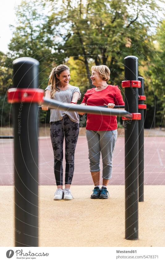 Grandmother and granddaughter training on bars in a park granddaughters grandmother grandmas grandmothers granny grannies exercising exercise practising parks