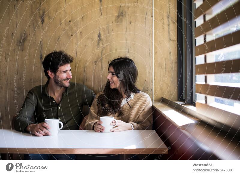 Happy couple drinking coffee in a cafe Tables smile Seated sit delight enjoyment Pleasant pleasure happy free time leisure time Lifestyle community Alimentation