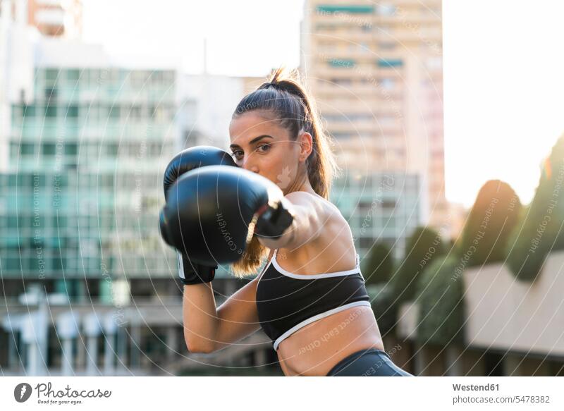 Portrait of sportive young woman boxing in the city portrait portraits females women sporting sporty athletic town cities towns Adults grown-ups grownups adult