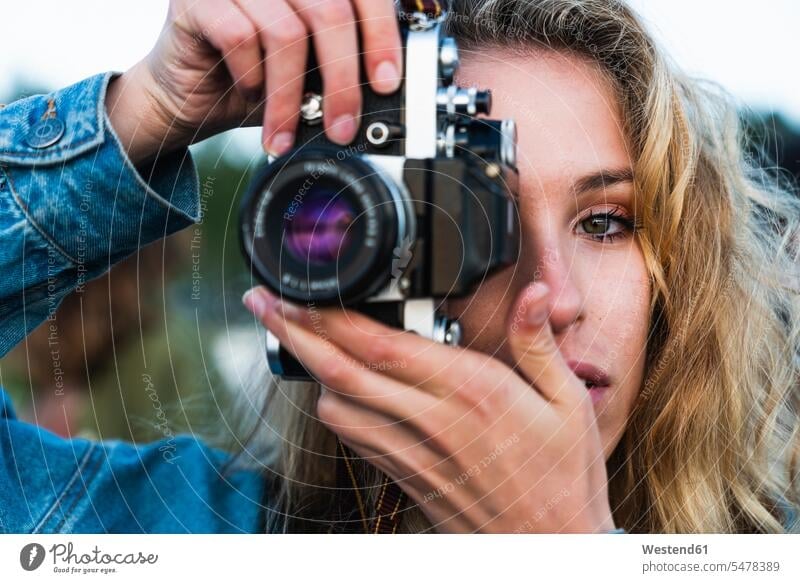 Close-up of beautiful blond young woman taking a picture with a camera blond hair blonde hair photographing portrait portraits cameras females women people