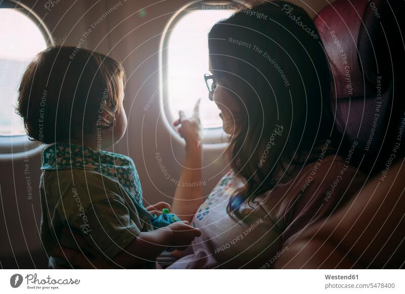 Mother and little daughter on airplane looking out of the window mother mommy mothers ma mummy mama journey travelling Journeys voyage air travel air travelling