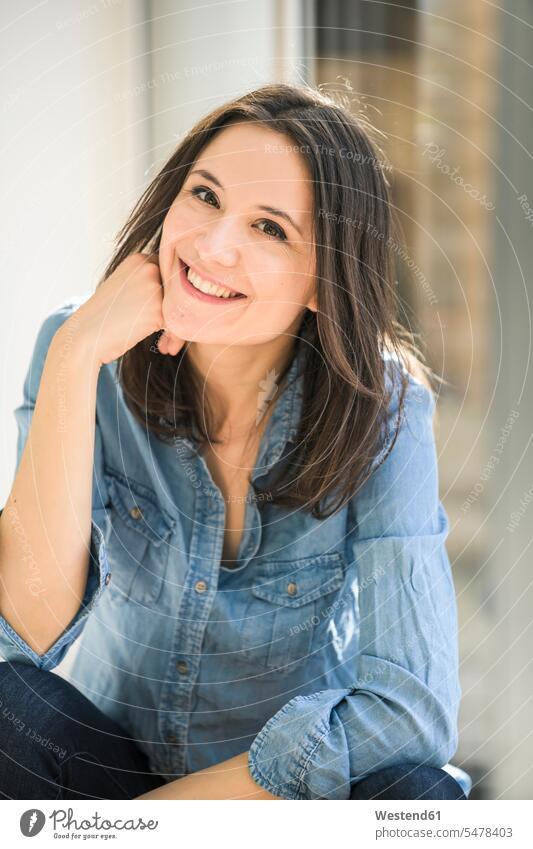 Portrait of happy woman wearing denim shirt at home sitting Seated happiness portrait portraits females women shirts Adults grown-ups grownups adult people