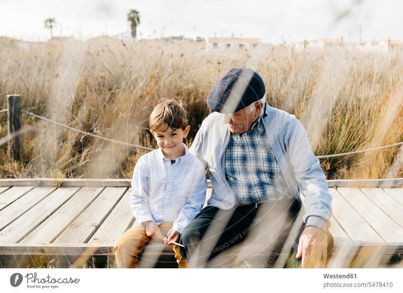 Grandfather sitting with his grandson on boardwalk relaxing caucasian caucasian ethnicity caucasian appearance european togetherness bonding Seated boardwalks
