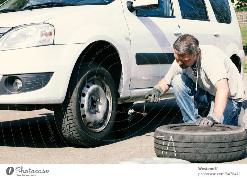 Mature man changing car tires, top view car tyre car tyres change tire change wheel change tyre change men males Adults grown-ups grownups adult people persons