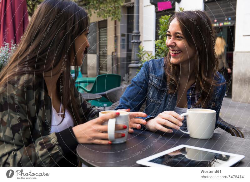 Happy young women having coffee sitting in outside cafe together in Madrid, Spain human human being human beings humans person persons caucasian appearance