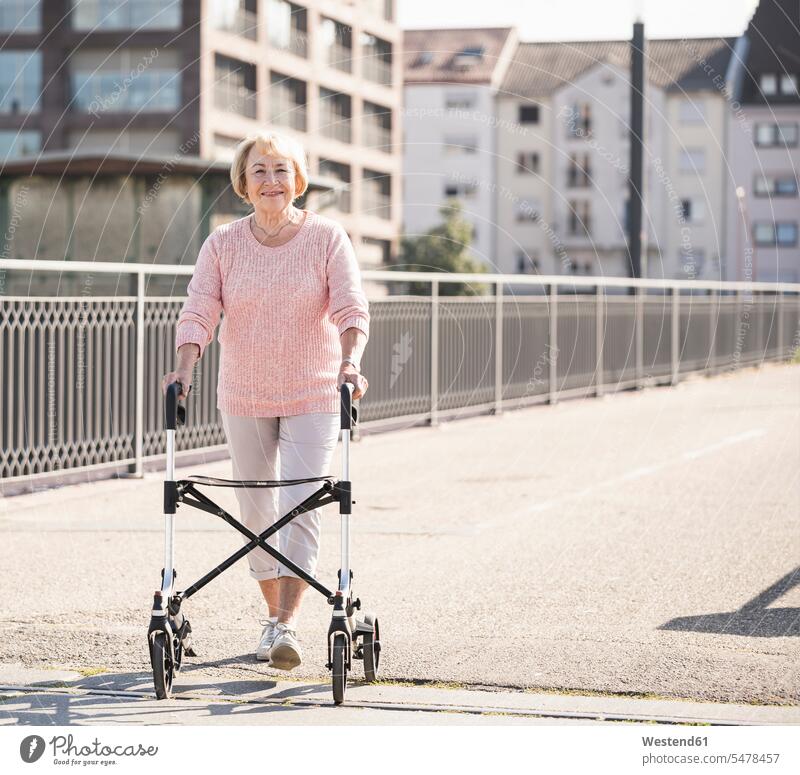Senior woman with wheeled walker on footbridge jumper sweater Sweaters go going hold colour colours Rosy Social Issue Social Theme Social Themes Social Topic