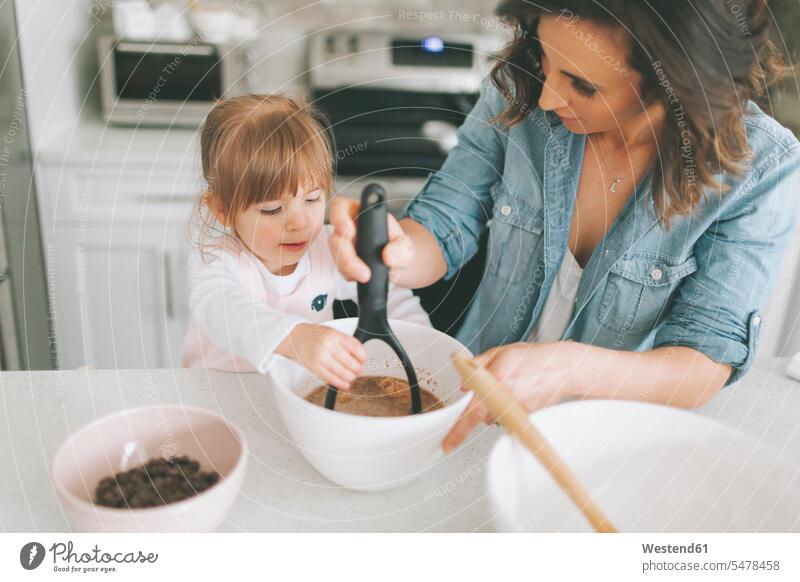 Mother and daughter making a cake together pies cakes stirring assistance assisting Help helping Making A Cake baking A Cake dough mother mommy mothers mummy