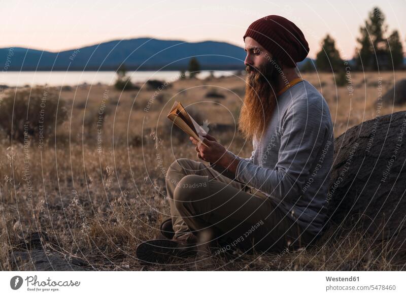 USA, North California, bearded young man reading a book near Lassen Volcanic National Park books men males people persons human being humans human beings Adults