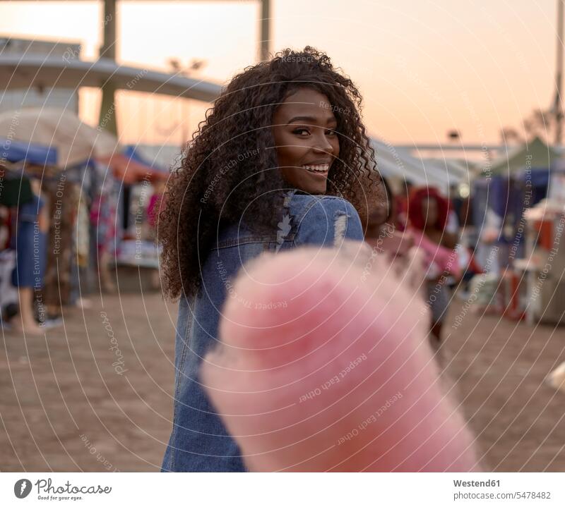 Portrait of happy young woman with pink candyfloss on street market smile in the evening delight enjoyment Pleasant pleasure Contented Emotion pleased colour
