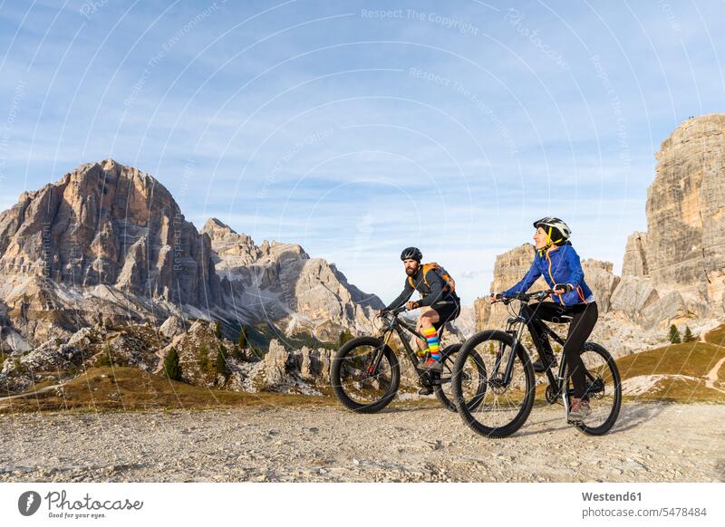 Italy, Cortina d'Ampezzo, two people cycling with mountain bikes in the Dolomites mountains riding bicycle riding bike bike riding bicycling pedaling